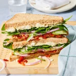 This protein-packed hummus sandwich features a topping of crisp veggies, feta cheese and sweet, tangy sun-dried tomatoes. Sun-dried tomatoes in oil have a soft texture perfect for sandwiches. You can use dry-packed sun-dried tomatoes in their place, but you may have to rehydrate them in water to soften them before using.